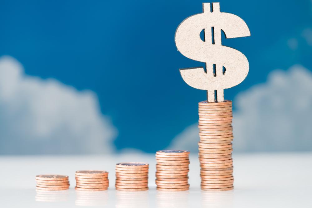 growing stacks of coins in front of a cloud backdrop